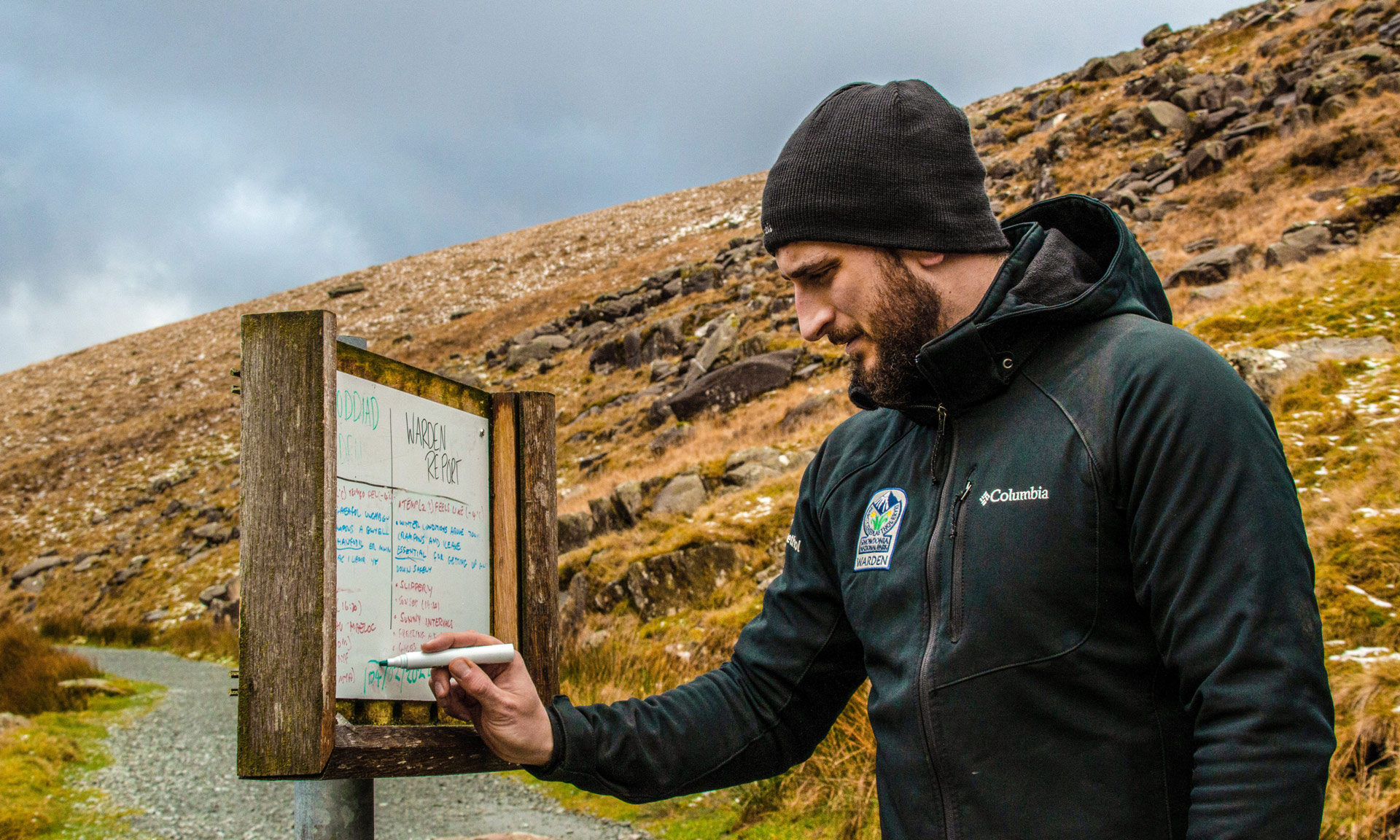 Snowdonia National Park Warden writes the ground condition report for Snowdon on a whiteboard along the Miners' Track